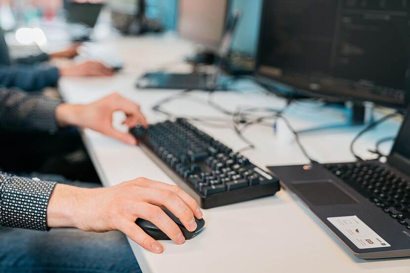 People are working on computers, but only hands and part of arms are visible.